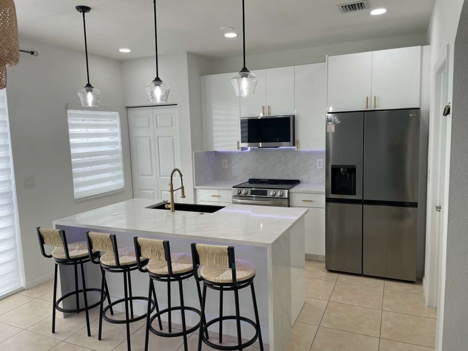 Completed New Season Designs kitchen with a white quartz island, gold hardware, and seating for four