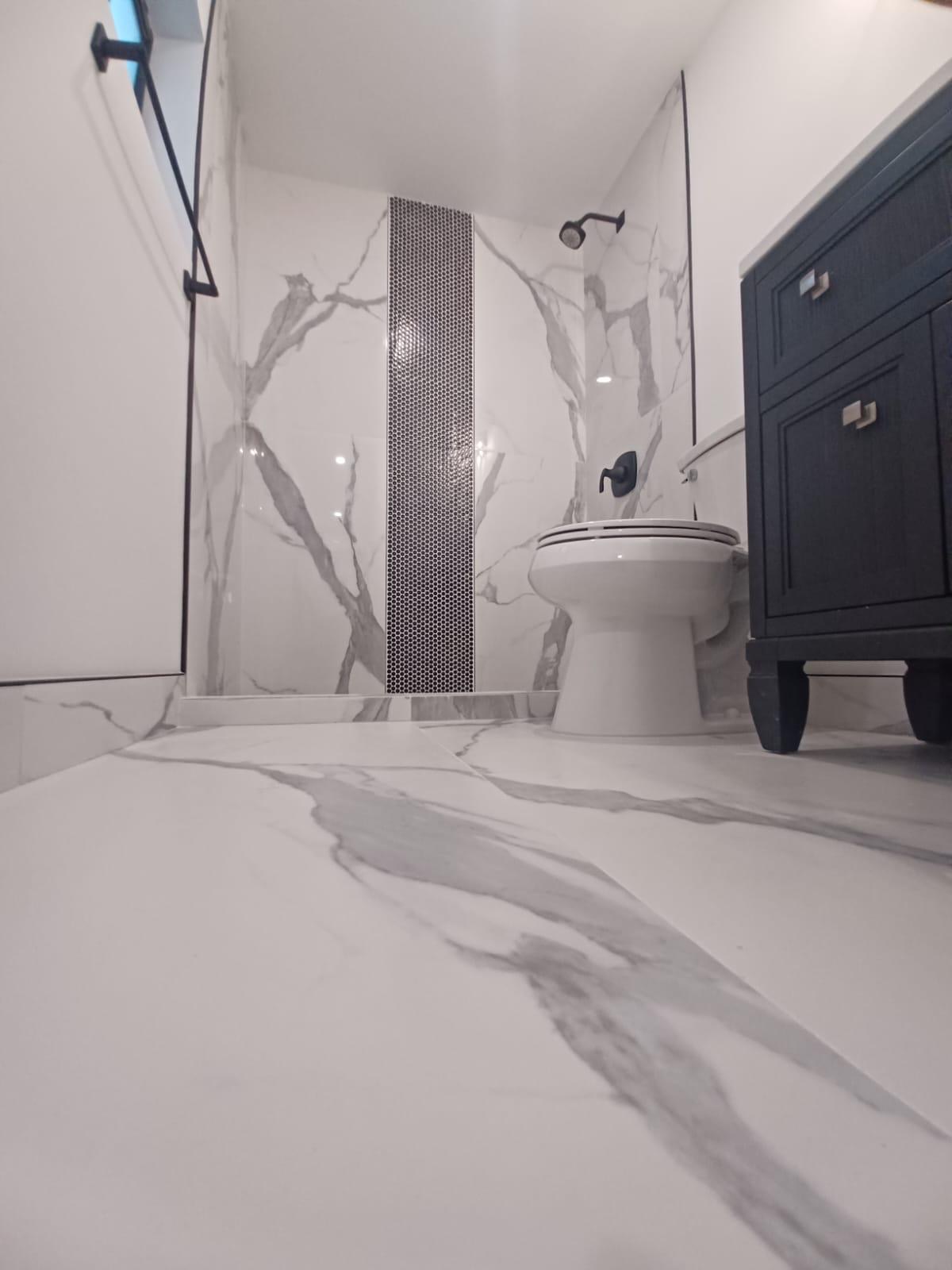 Marble-look walk-in shower — finish detail from a completed renovation