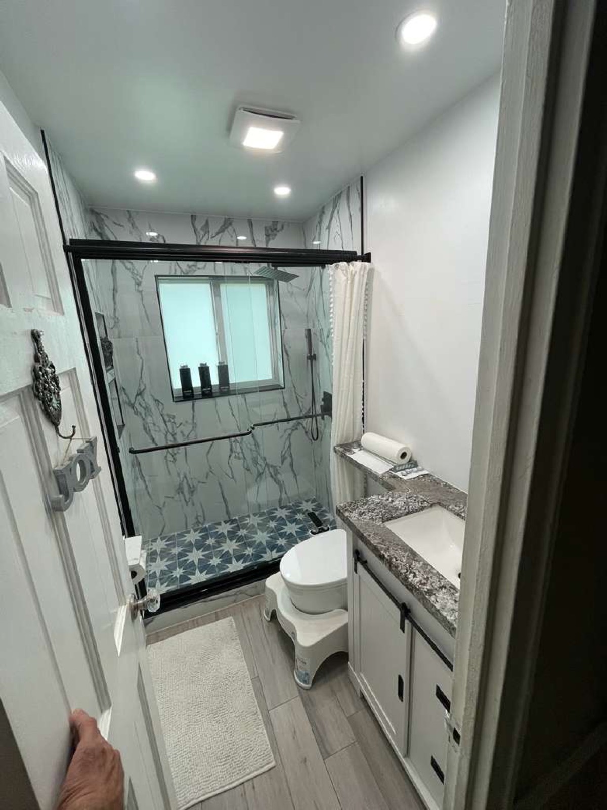 Finished guest bath — marble-look shower surround with star-pattern floor tile