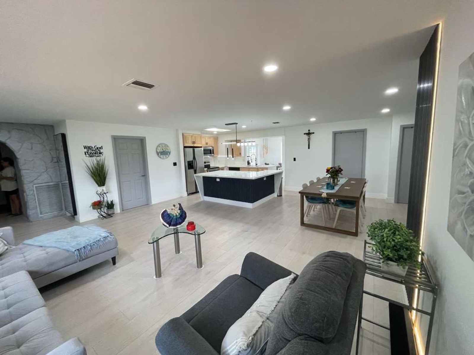 Completed New Season Designs open-concept great room with a navy kitchen island and wood-look flooring