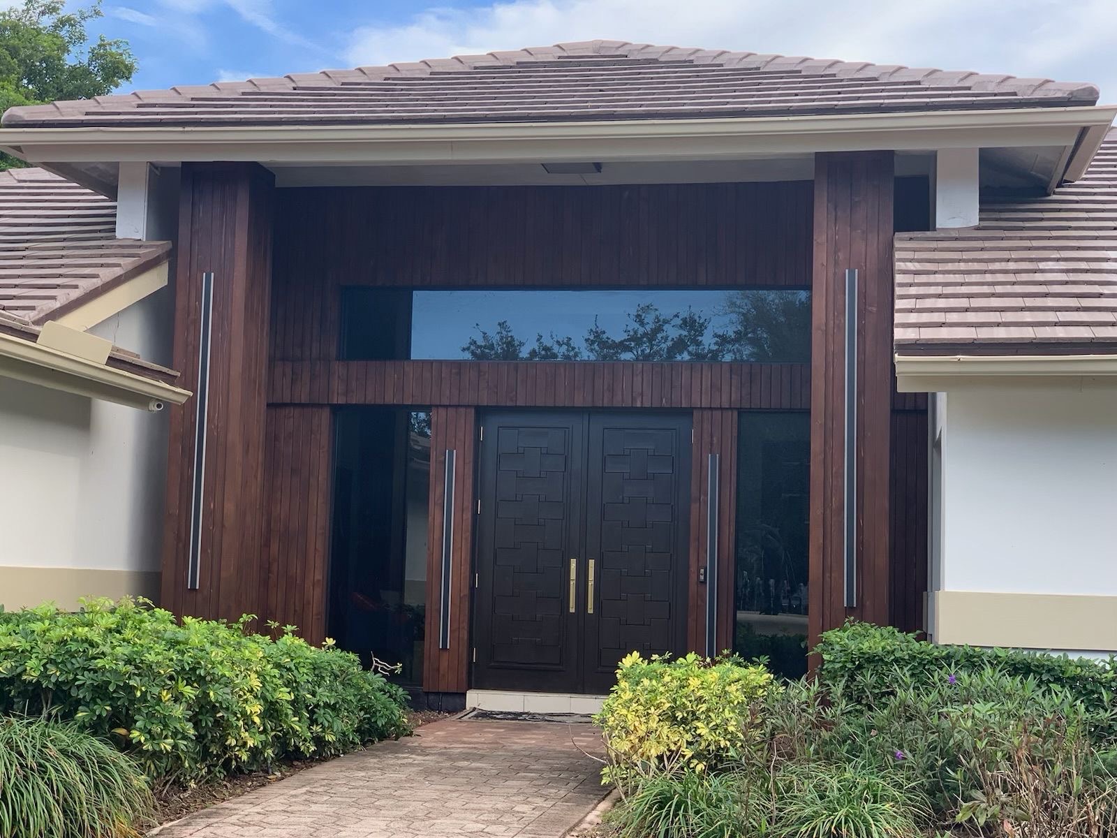 Entryway after — refinished wood columns, carved double doors, and transom glass