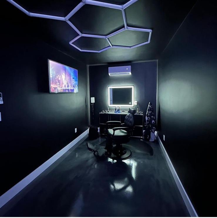 Garage after — finished black-walled barbershop studio with epoxy floor and hexagon LED ceiling lights