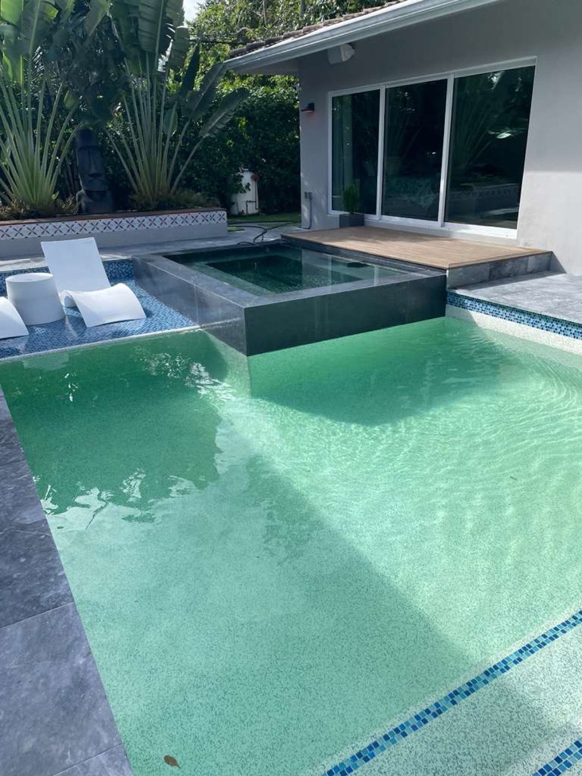 Pool and spa during construction — bare gray-tile shell with unbalanced green water