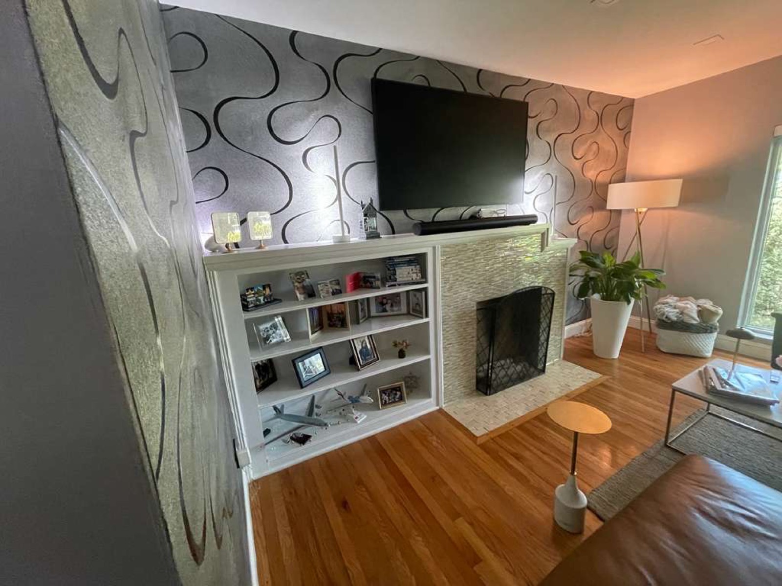 Finished living room — custom white built-in bookshelf and tiled fireplace surround