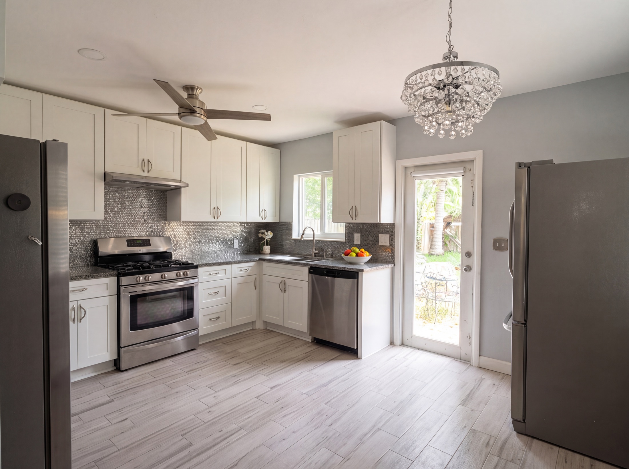 Kitchen after — white shaker cabinets with gray glass-mosaic backsplash