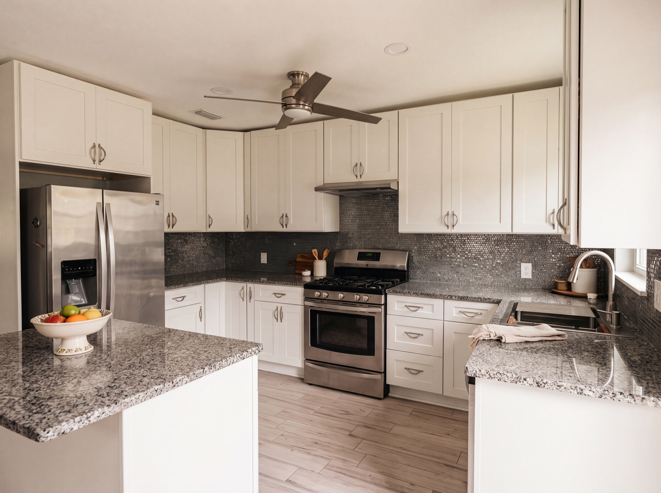 Kitchen after — refaced white shaker cabinets and gray plank flooring