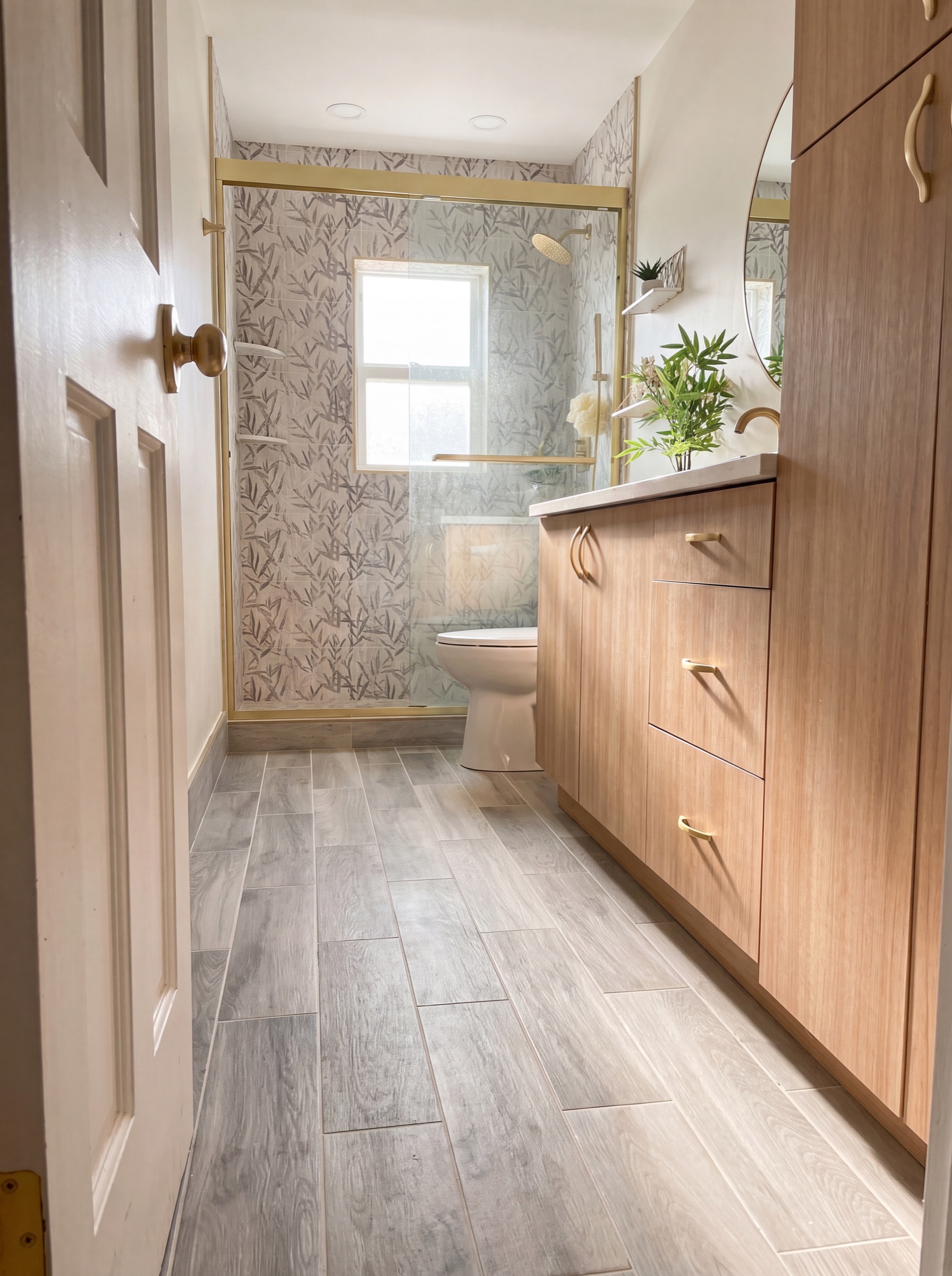 Bath after — botanical-tile shower with gold-framed glass